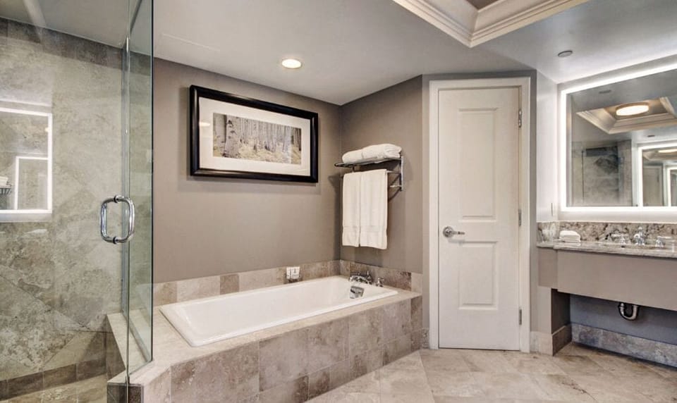 Relax and unwind in the luxurious bathroom featuring a spacious glass-enclosed shower and a separate soaking tub. The modern design is complemented by elegant fixtures and ample counter space, ensuring a spa-like experience.