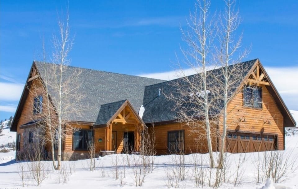 Mountain lodge with rustic charm surrounded by pristine winter landscape and snow-capped peaks.