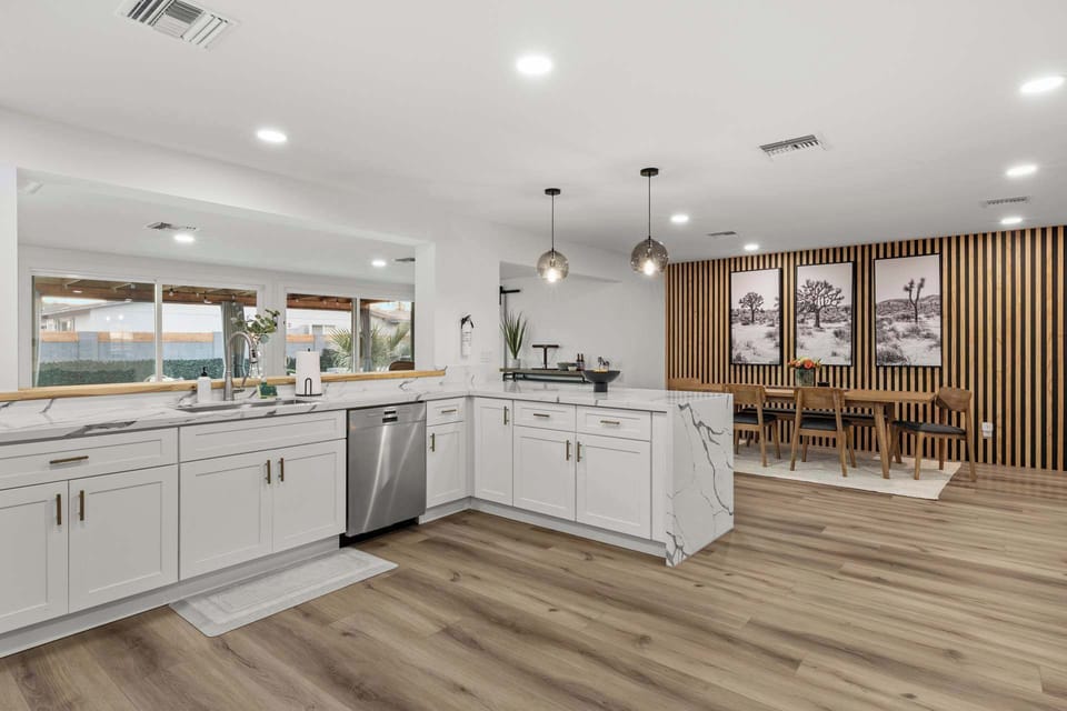 Elegant marble bar seamlessly connects to a dining area bathed in natural light through large windows.