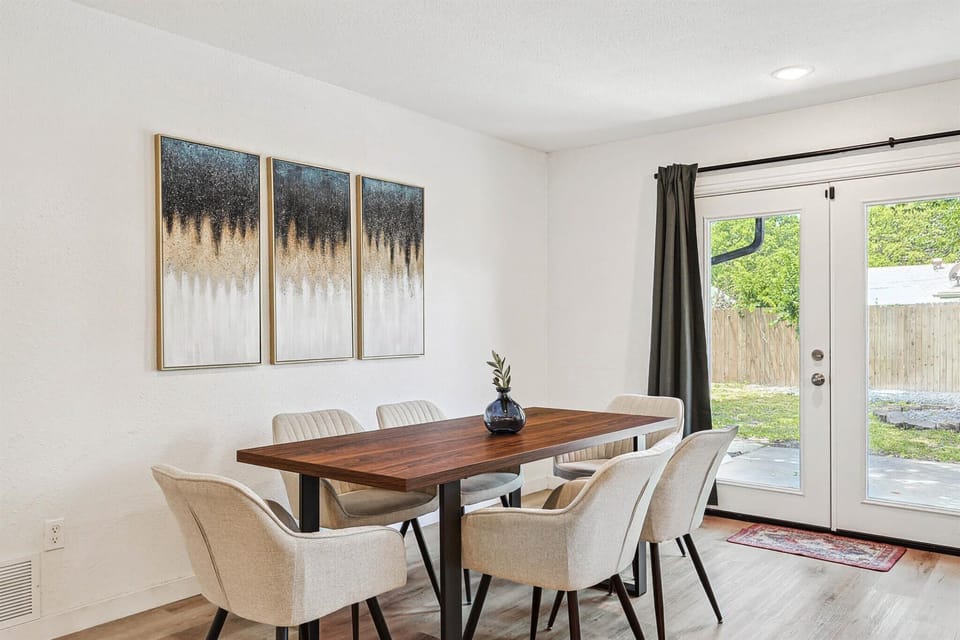 This mid-century modern dining room offers a restaurant-like environment for your meals with curated artwork and plenty of natural light from the French patio doors.