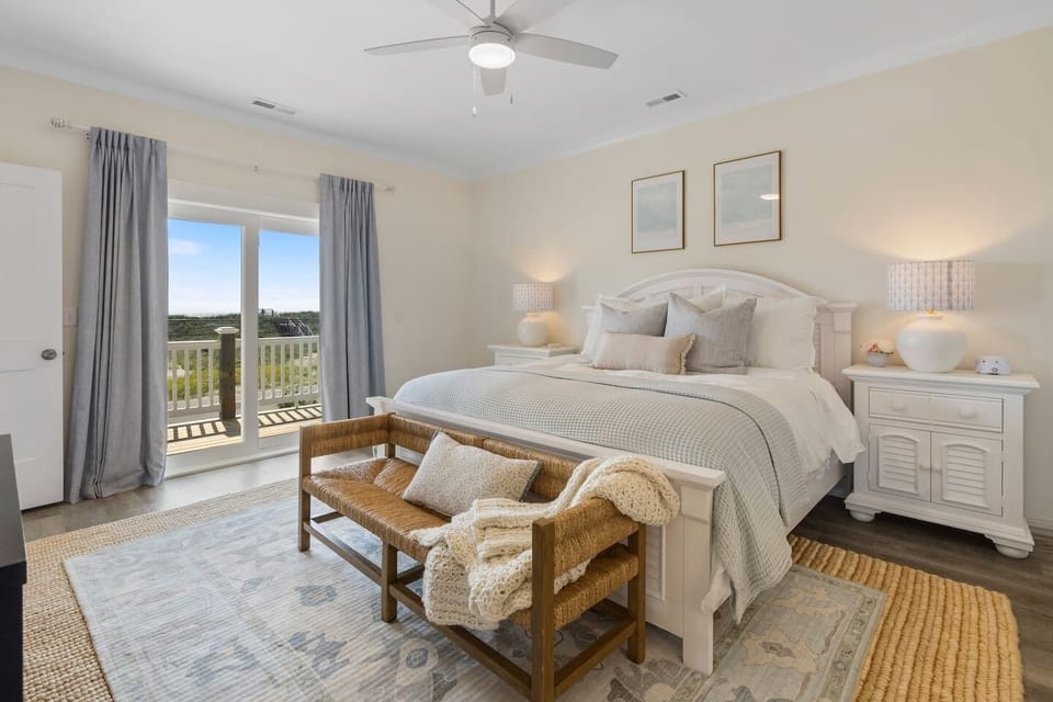 This bedroom features a cozy king bed, a woven bench, and a sleek navy dresser for ample storage.