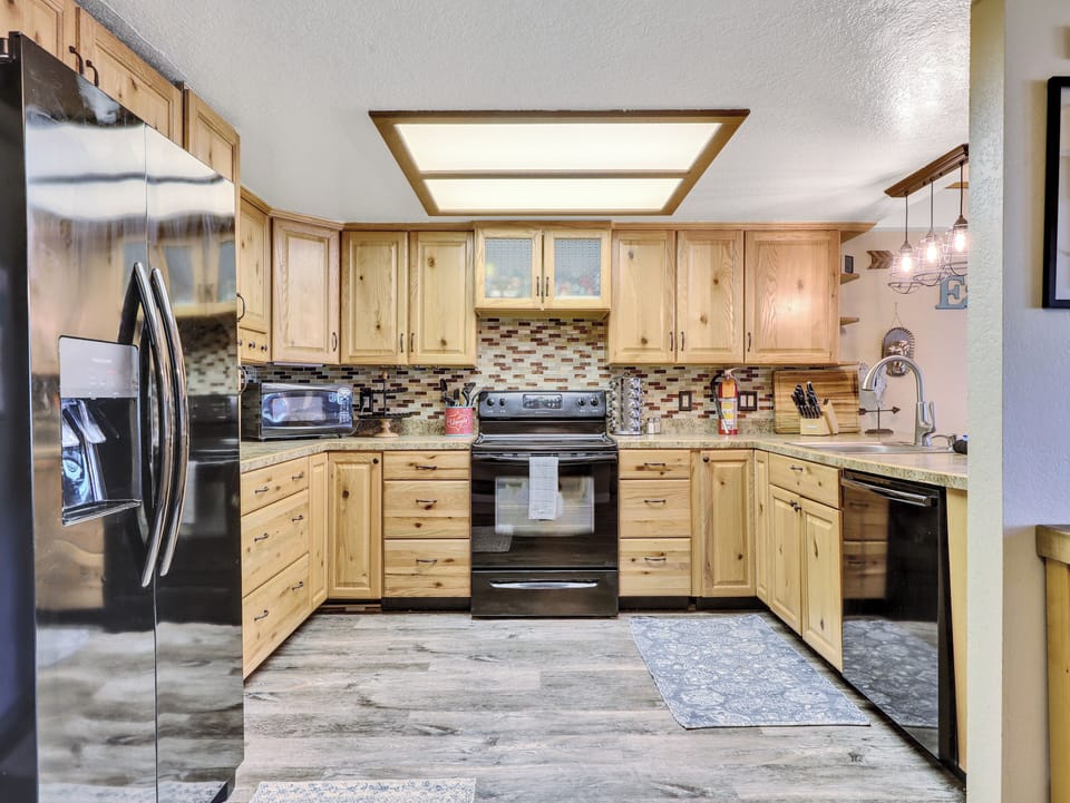 View of Kitchen Refrigerator, ample counter space, dishwasher, electric stove & oven, cooking spices, knife block, microwave, wood cabinetry, coffee maker