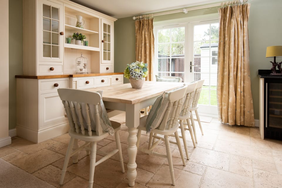 Light & airy dining area with farmhouse table & french doors opening onto back garden