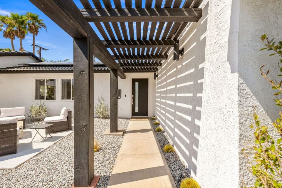 Shaded entry walkway w/ pergola details and textured walls that set a relaxed desert tone on arrival.