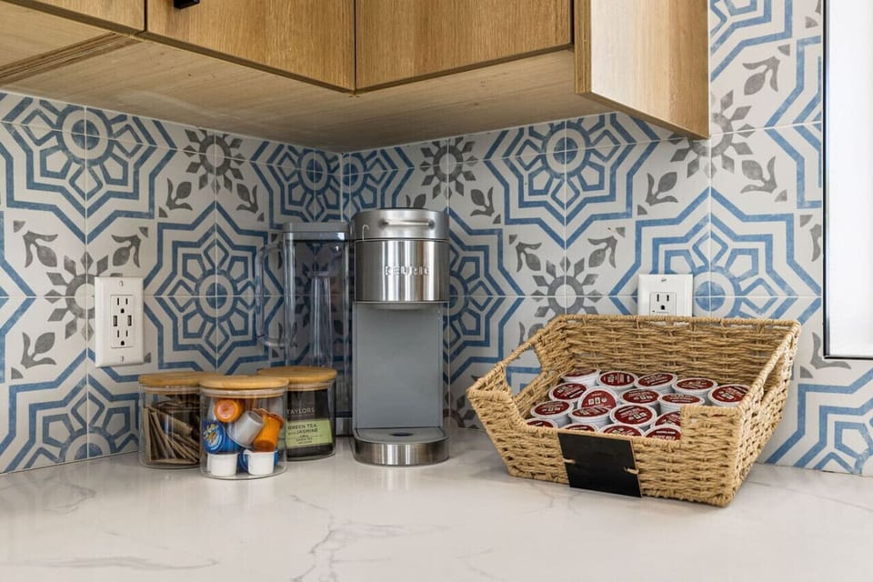 Cozy nook w/ bold patterned walls, layered textures, and seating that adds character and charm.