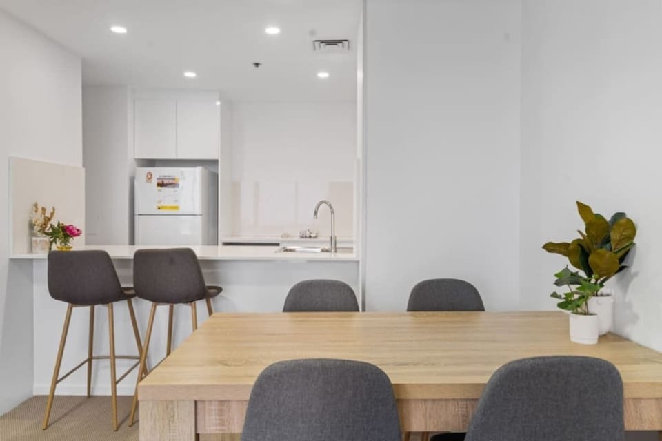 A timber dining table and bar stools complement the inviting ambiance of this property, offering a stylish and comfortable space for meals and gatherings.