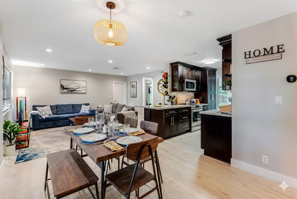Bright open living-dining area flowing into modern kitchen, warm neutral tones.