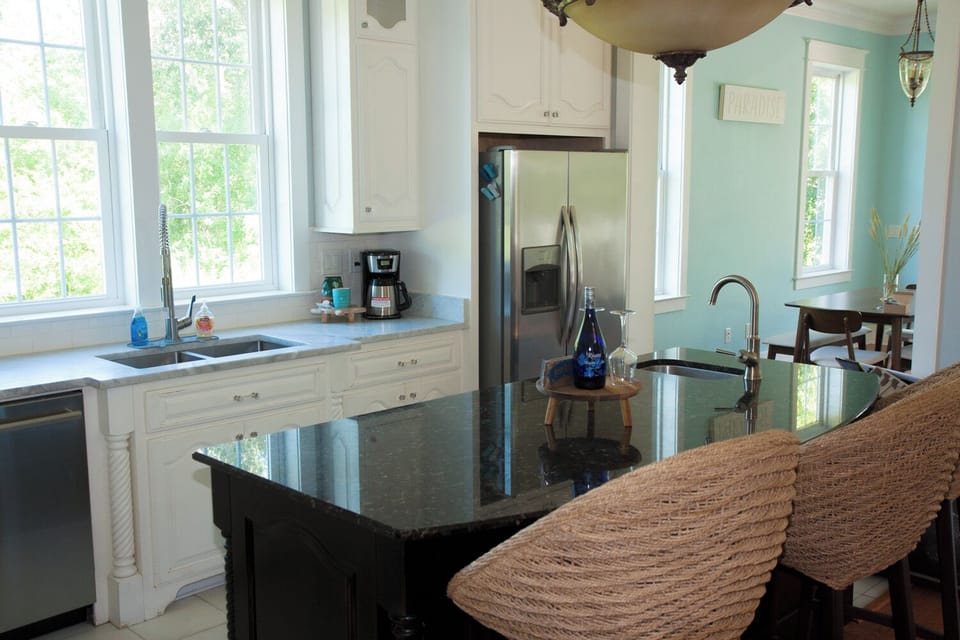 Kitchen with large windows and kitchen island with seating and prep sink.