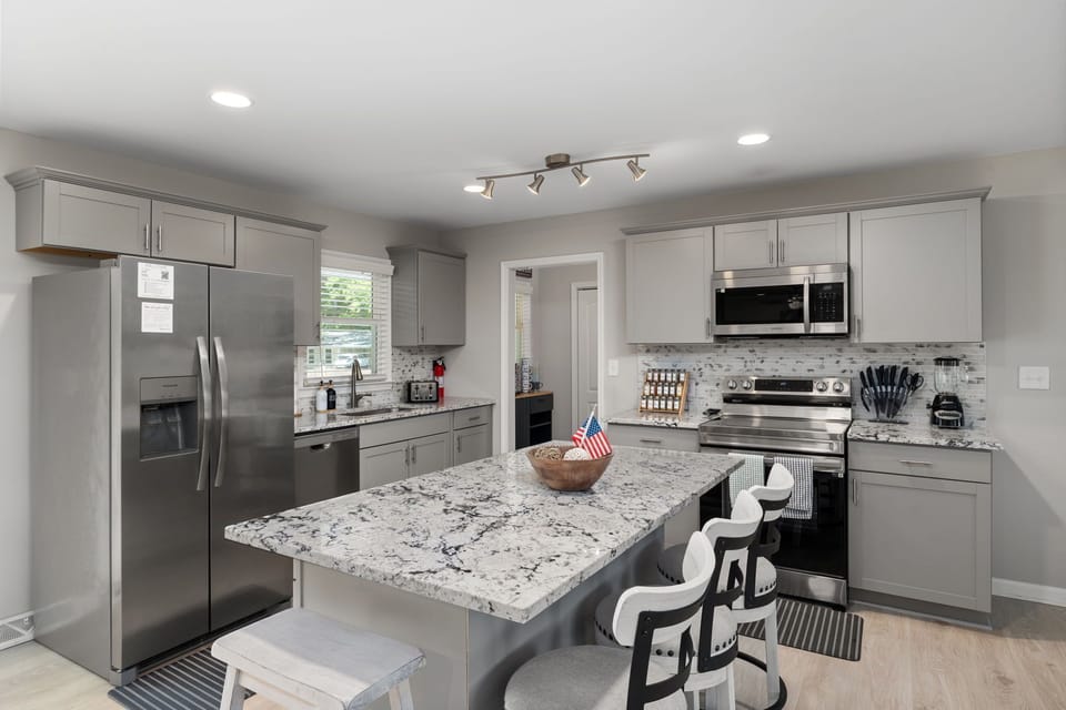 Bright modern kitchen with granite island, seating, and stainless appliances
