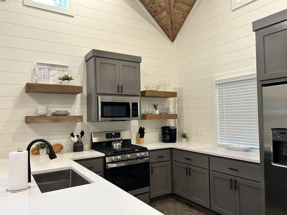 Cozy farmhouse kitchen with gray cabinets, open shelves & rustic charm.