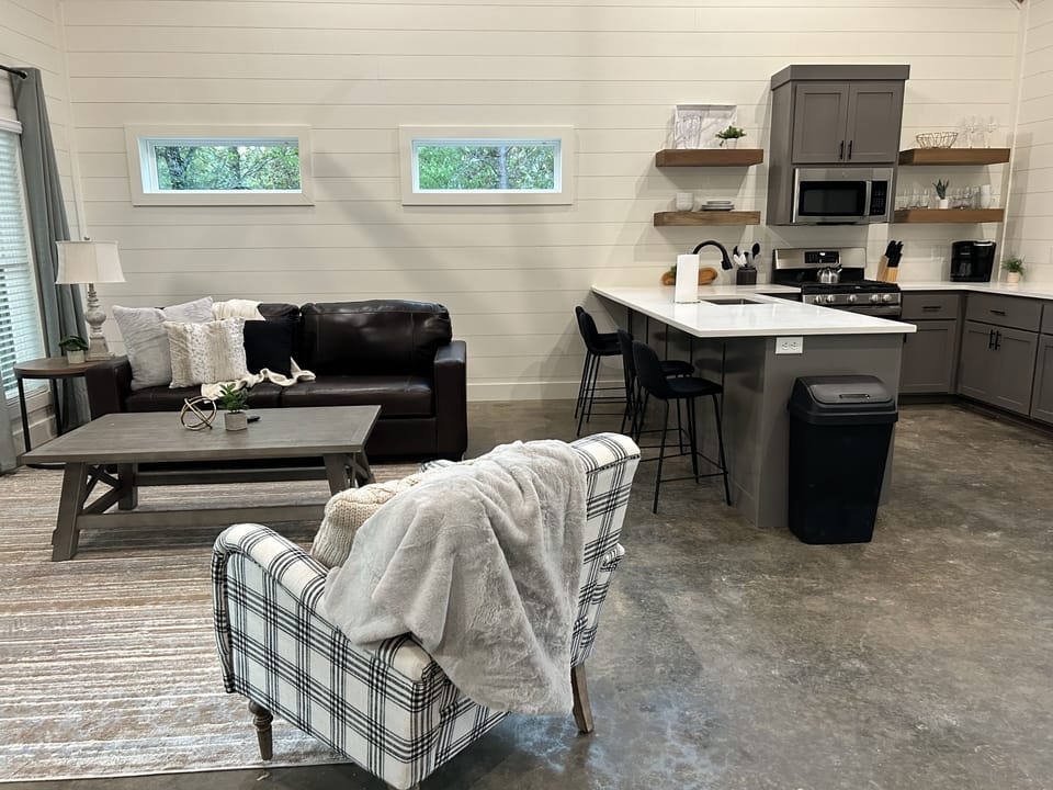 Cozy open living room & kitchen with leather sofa and warm lighting. 