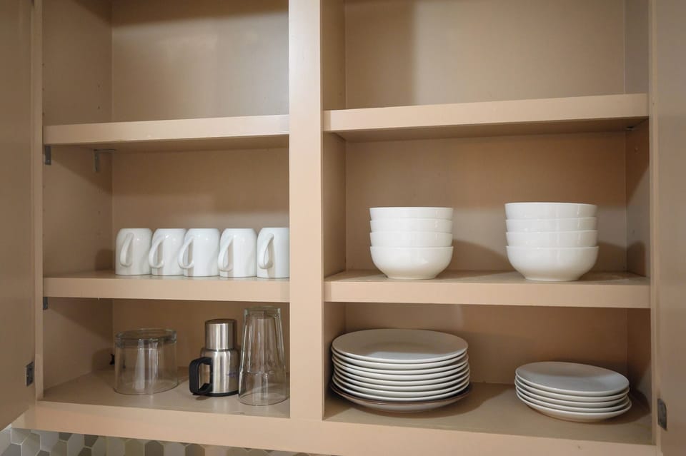 Kitchen stocked with extra mugs, dishes, bowls, and glasses.
