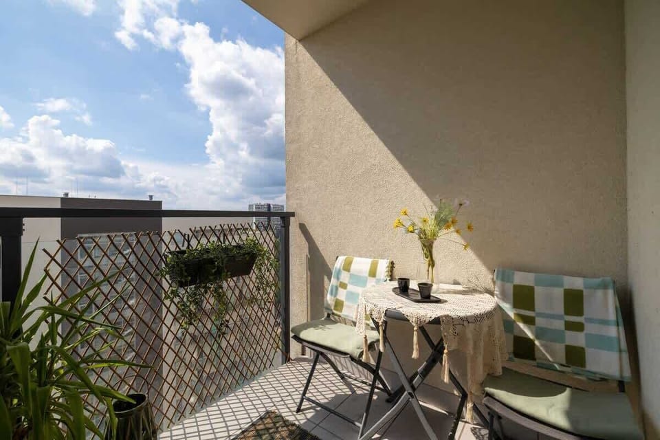 A sunny balcony with chairs and a table creates a space to enjoy a coffee. 