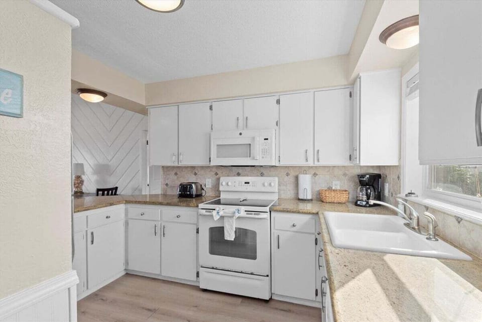 Bright beachfront kitchen with ample counter space, modern appliances, and open layout for cooking during family beach getaways.