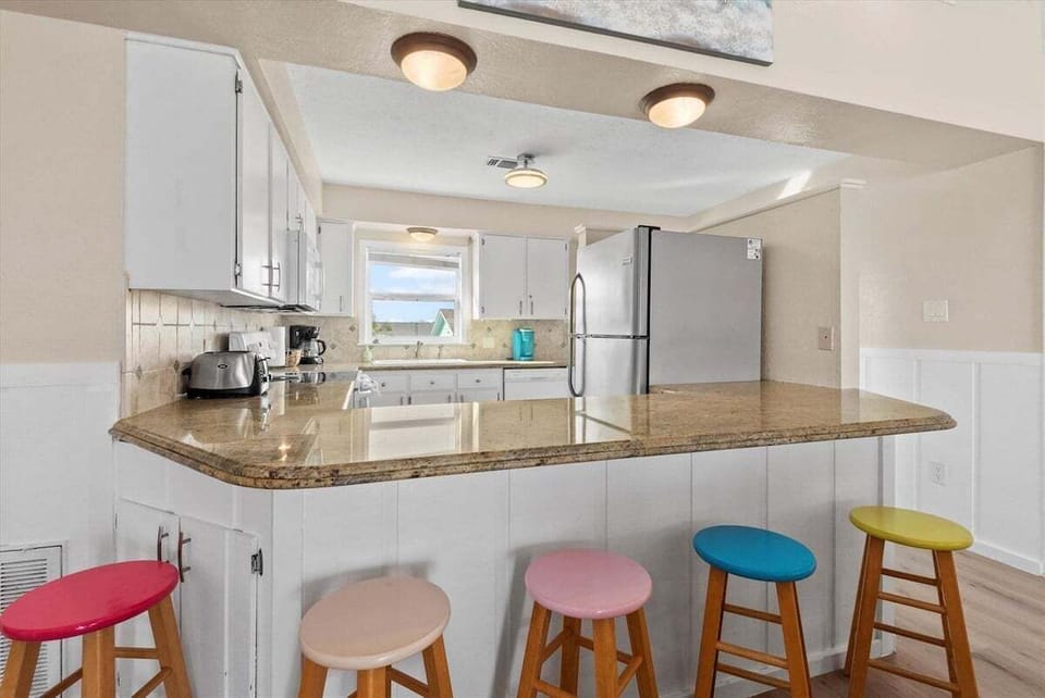 Spacious beach house kitchen with wraparound breakfast bar, modern appliances, and open entertaining space near the Gulf Coast.