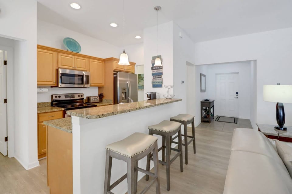 An eating bar with 3 bar stools separates the open kitchen from the main living space.