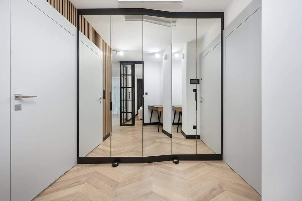 A hallway view showing elegant storage solutions and modern design. White and wooden tones dominate the space.

