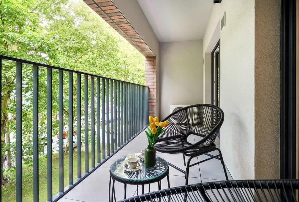 A cozy balcony with a small table and chairs overlooking a green courtyard. Ideal spot for morning coffee or evening tea.