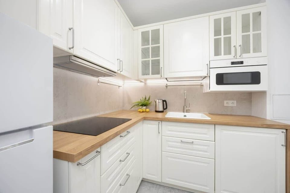 Fully equipped kitchen with refrigerator and freezer, induction cooktop, electric kettle, microwave and washing machine.