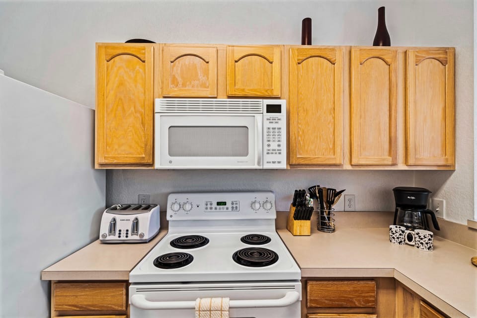 Functional kitchen corner with essential appliances: microwave, stove, and toaster - Practical countertop space for meal preparation and cooking - Wooden cabinets provide storage, complemented by a convenient coffee maker for your morning brew