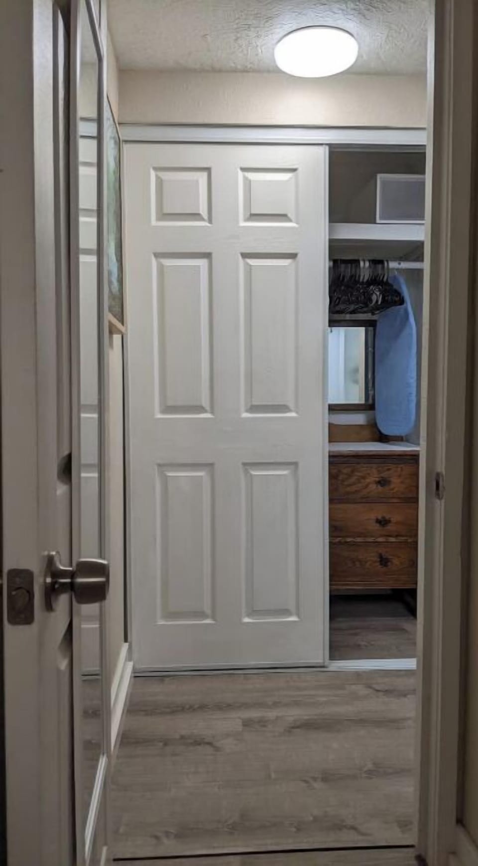 Dresser is located in the closet, with hangers, iron, and small ironing board.