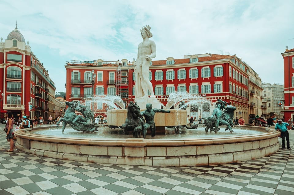 The Fontaine du Soleil presides over the vibrant Place Masséna, Nice's sun-drenched central square framed by bold red Italianate facades.