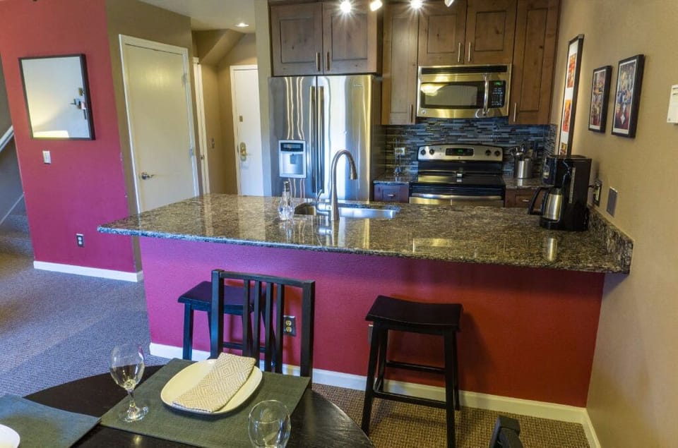 The contemporary kitchen includes a breakfast bar, granite countertops, and top-of-the-line stainless steel appliances.