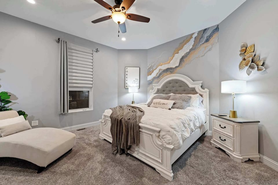 Spacious bedroom w/ soft tones, cozy bedding, and a calm layout made for easy rest.