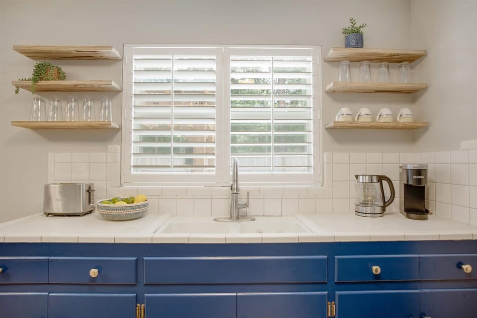 "Sleek Design & Fully Stocked Essentials"
Our kitchen is thoughtfully organized with everything you need within reach. From the deep farmhouse-style sink to the stylish open shelving and vibrant blue cabinetry.