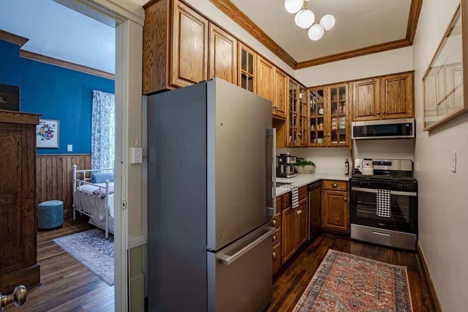 Bright kitchen w/ wood cabinets, stainless fridge & window light filling the space