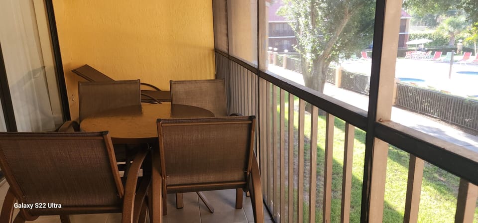 Balcony equipped with table, chairs and lounge chair overlooking pool