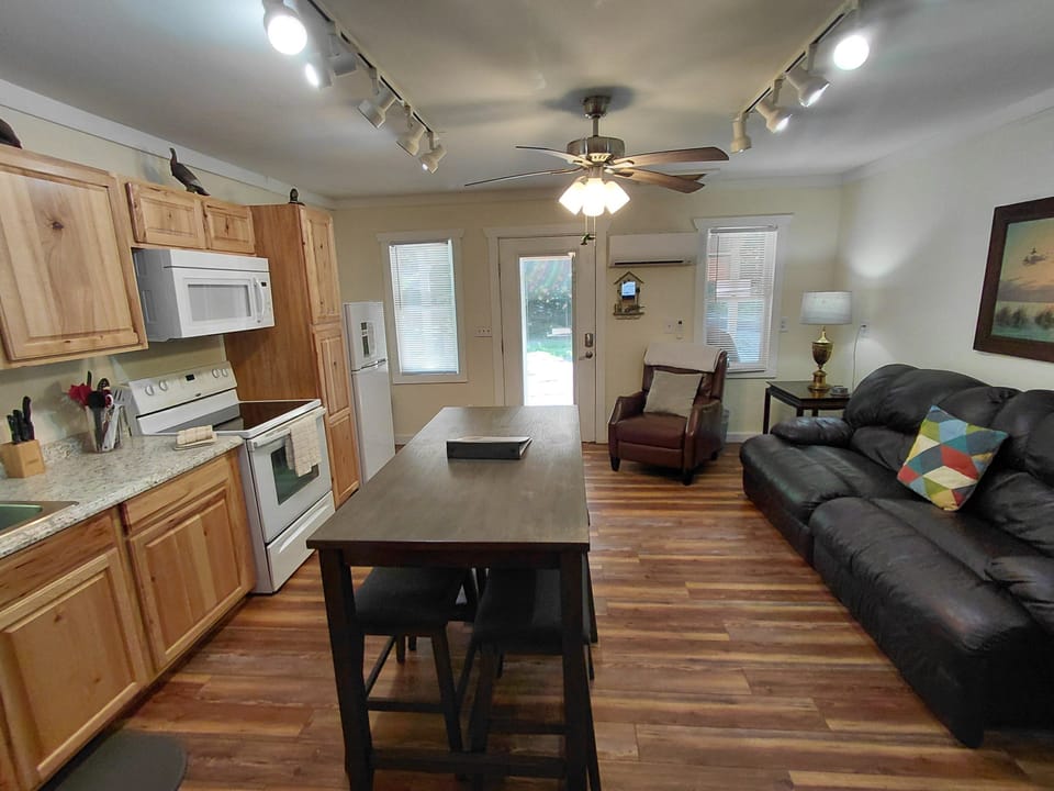 Open-concept interior featuring kitchen cabinetry, dining island, living room seating, and wood flooring. Functional layout for vacation stays near the Smoky Mountains.