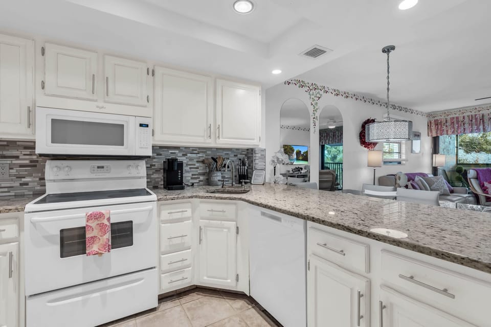 The kitchen features granite counter tops and white appliances and cabinets