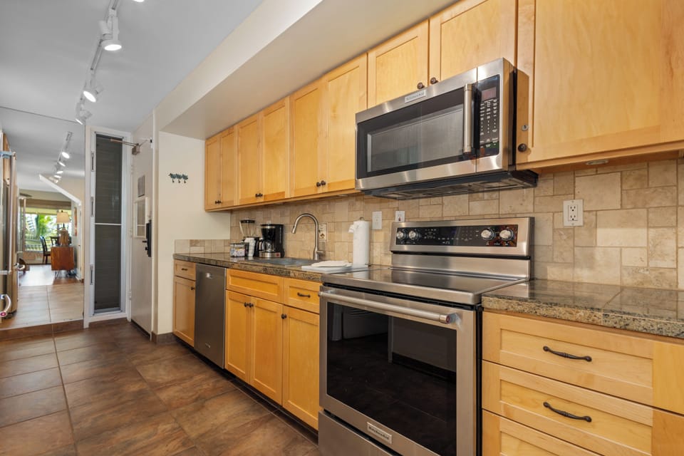 Your fully equipped kitchen features stainless steel appliances, granite countertops, and warm wood cabinetry—perfect for preparing your favorite meals during your stay.
