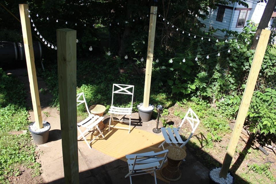Backyard space with 4 chairs, 1 center table (not shown), solar stringed lights
