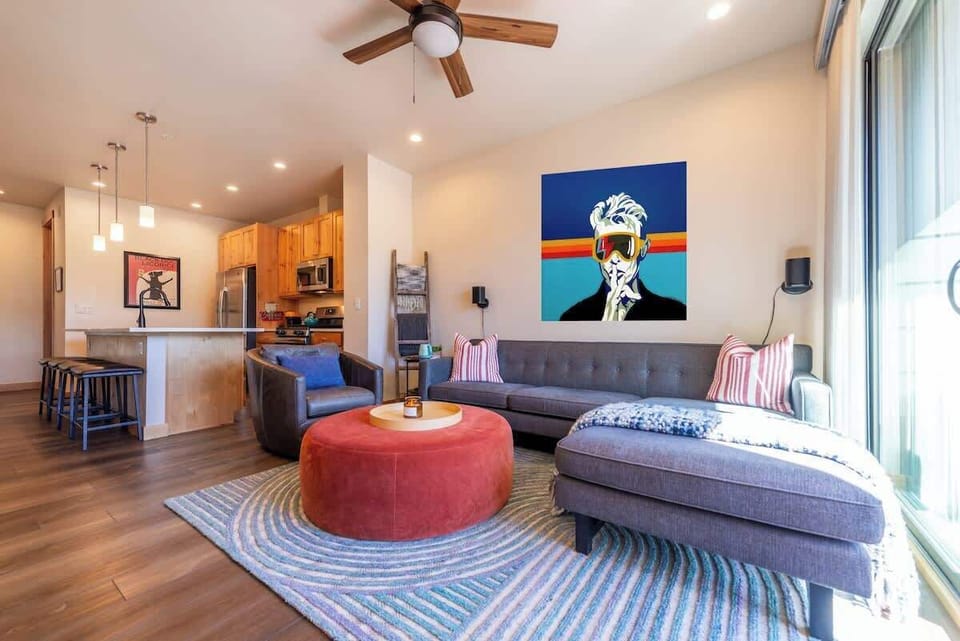 - Stretch out in this bright living room featuring a charcoal sectional and vivid abstract decor
- Open layout flows into a sleek kitchen and breakfast bar, ideal for groups
- Stylish, functional, and full of personality from wall to wall