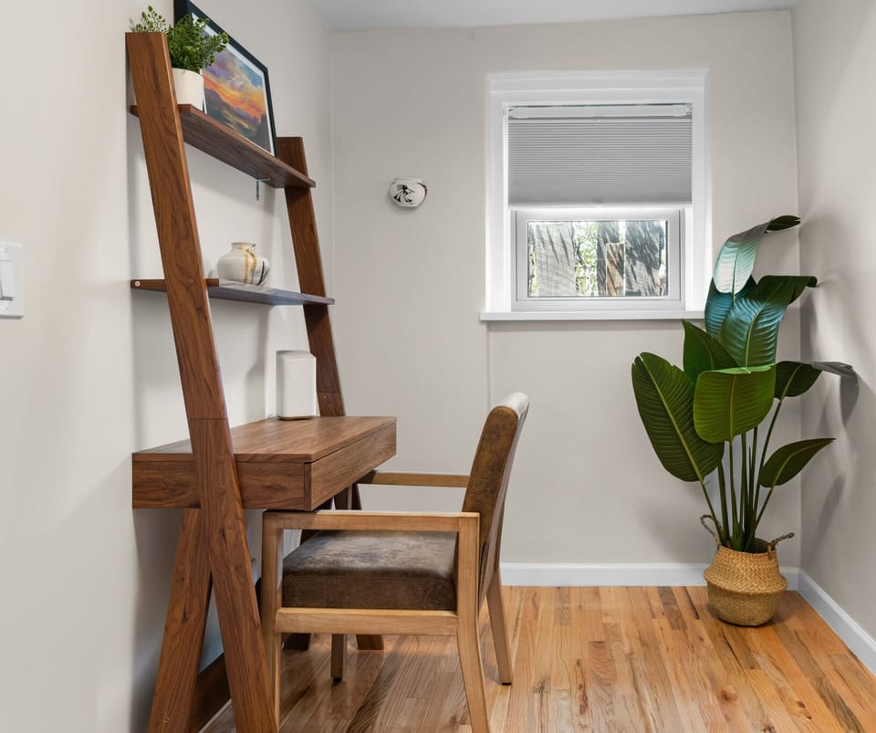 Minimalist workspace with wooden desk and leafy plant.