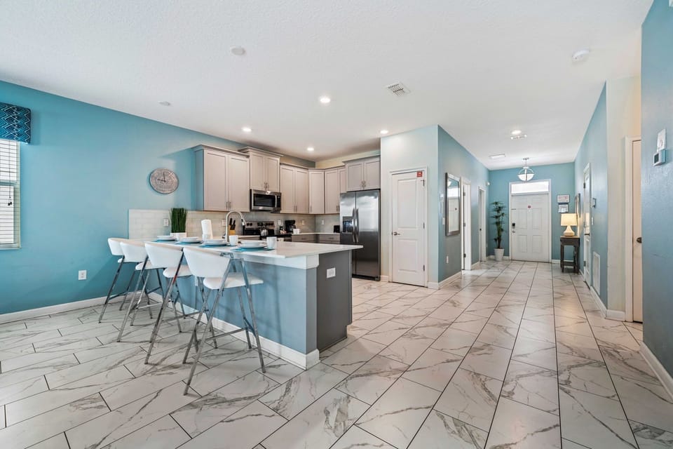 - Contemporary kitchen with stainless steel appliances and a sleek design - Large island with bar seating, perfect for casual dining or socializing while cooking - Bright and airy space with plenty of natural light and elegant tiled flooring