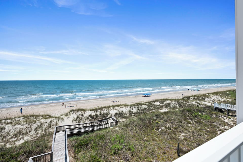Wide beachfront views with boardwalk access to the sandy shore and rolling waves—proximity to this coastal beauty is just outside the property.