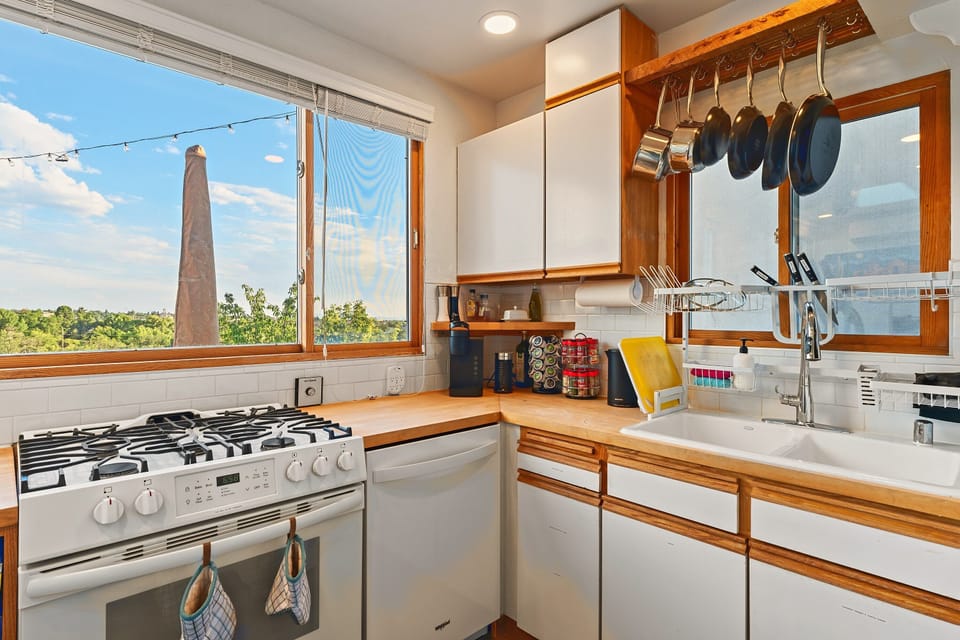 Gas range, dishwasher, and a window that looks out over the treetops.