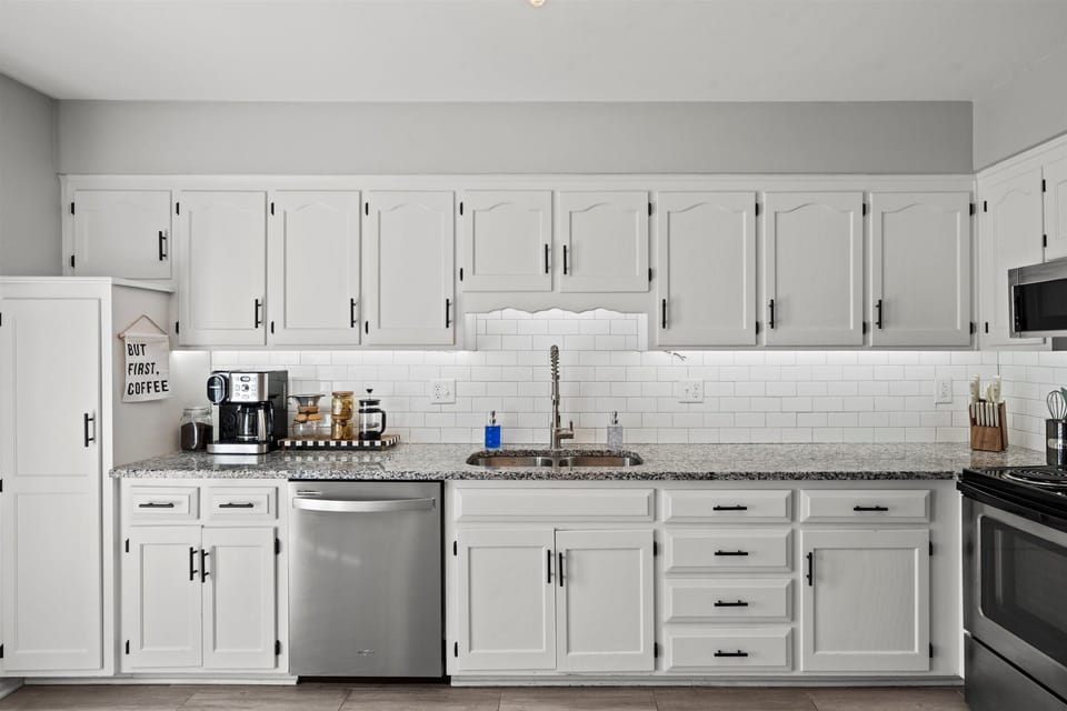 Bright, fully equipped kitchen with ample cabinetry, stainless steel appliances, and clean subway tile backsplash.
