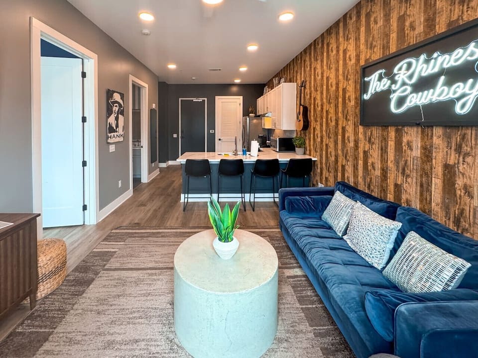 Living room w/velvet sofa, open floor plan to kitchen and breakfast bar area
