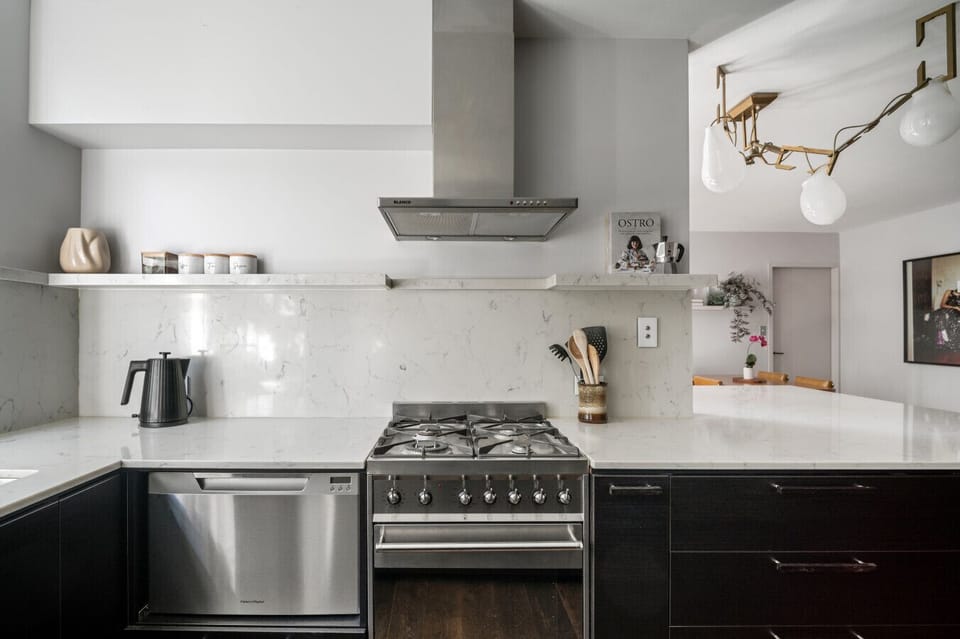 This stylish kitchen boasts sleek stone benchtops, stainless steel appliances, a gas cooktop, and thoughtful touches that make cooking a breeze