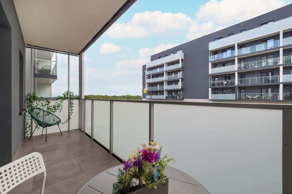 Urban balcony space with potted flowers and a view of nearby apartment blocks.