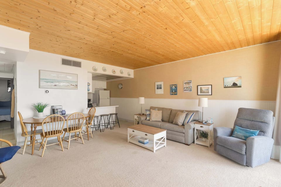 Warm and inviting living room featuring a cozy fireplace and plenty of seating tying in a dining table.