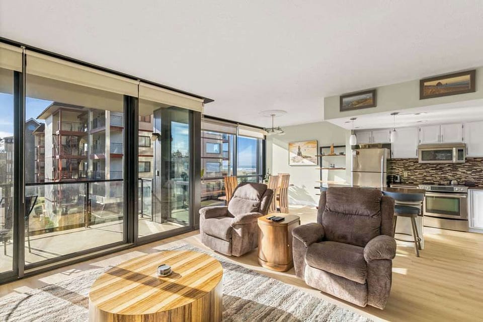 Sun-filled open living space with balcony access, comfy seating, and a fully equipped kitchen.