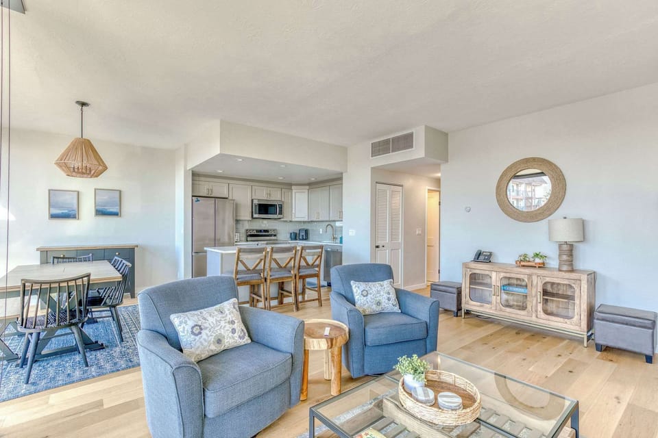 Modern open-concept living space with large windows, cozy seating, and spacious dining—bright, inviting, and perfect for your relaxing beachfront getaway.