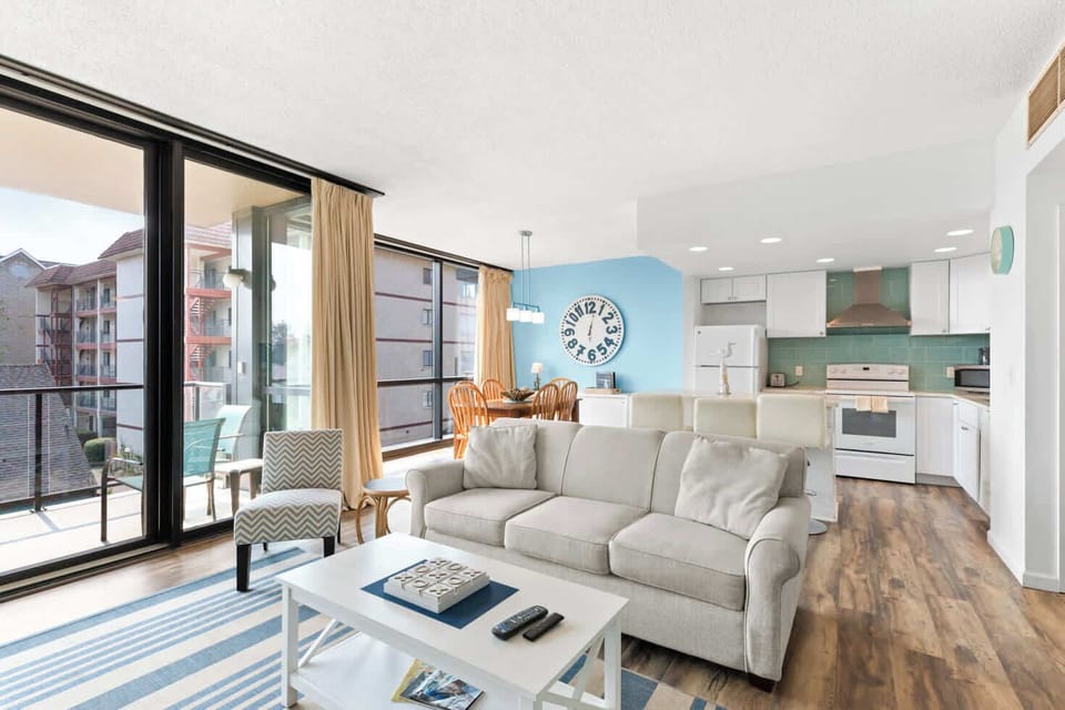 A modern, open-concept living space with large windows, cozy seating, a spacious dining area, and a bright, inviting atmosphere.