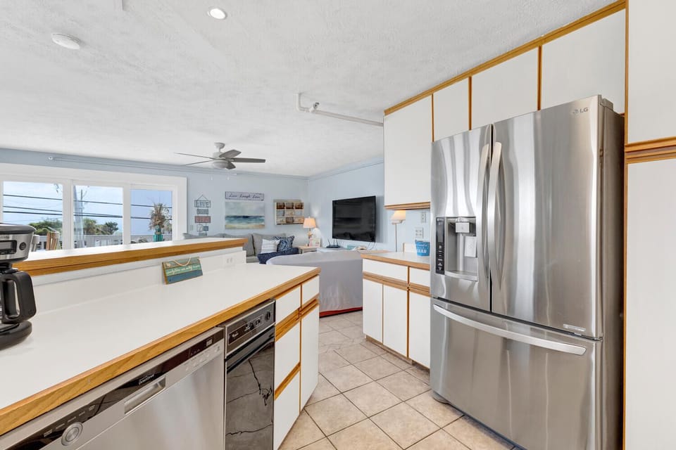 Your beachy kitchen features modern stainless appliances and breezy ocean views through the windows—perfect for morning coffee or prepping meals in style.