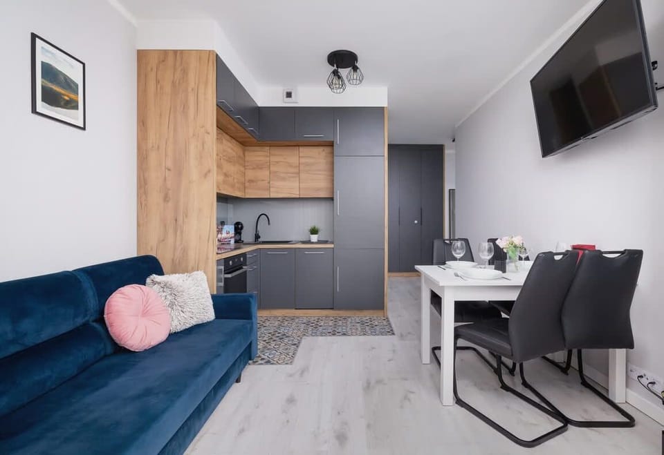 Cozy living area with a sofa and dining table next to the wall-mounted TV.